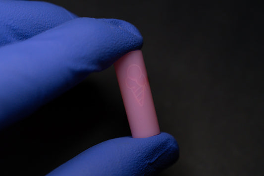 A gloved hand holds a PINK CONEZ cylindrical item from the brand CONEZ, featuring an ice cream cone design, against a dark background.