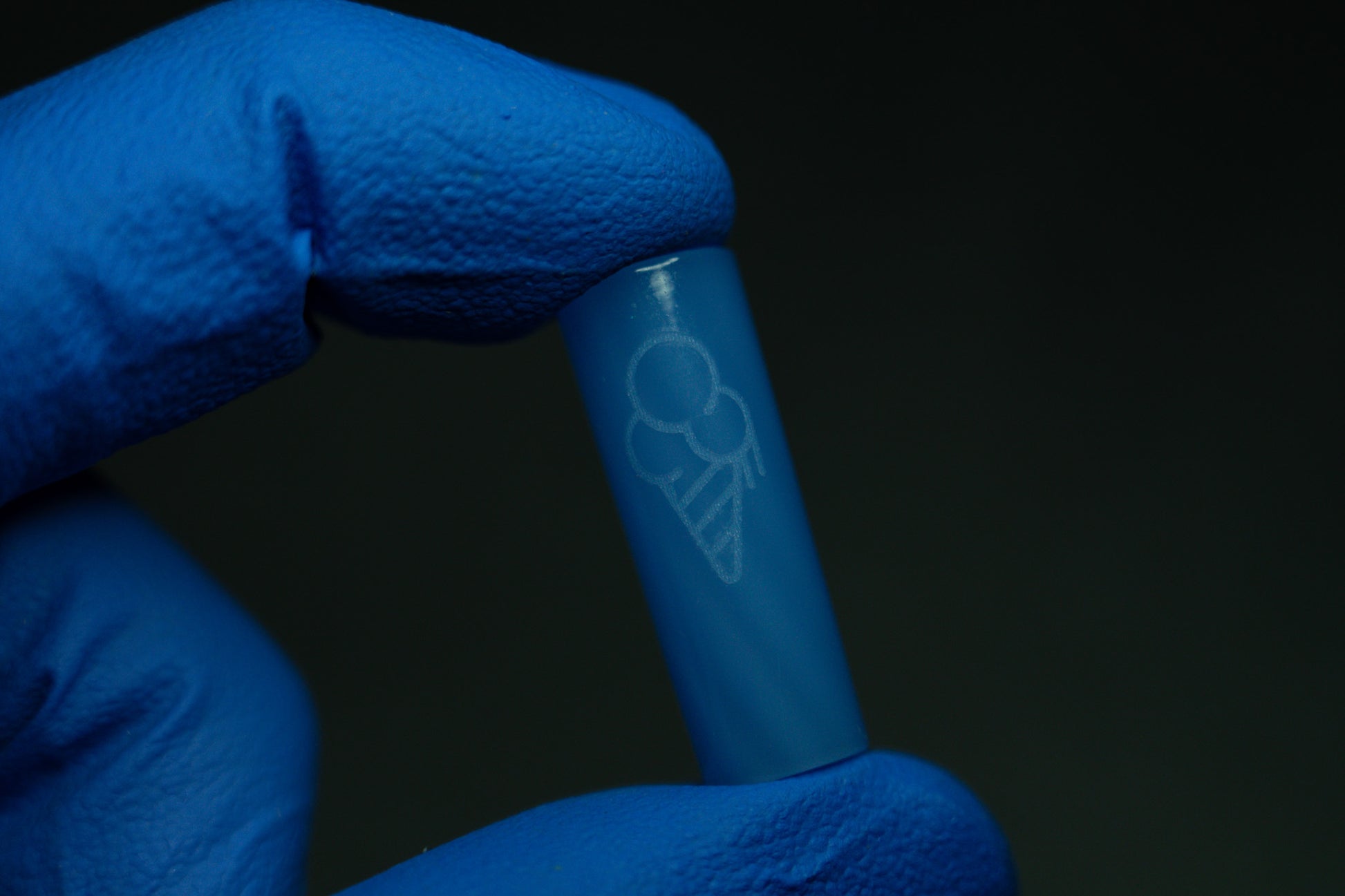 A hand wearing a blue glove holds a BLUE CONEZ capsule from the CONEZ brand, featuring a white ice cream cone outline, set against a dark background.