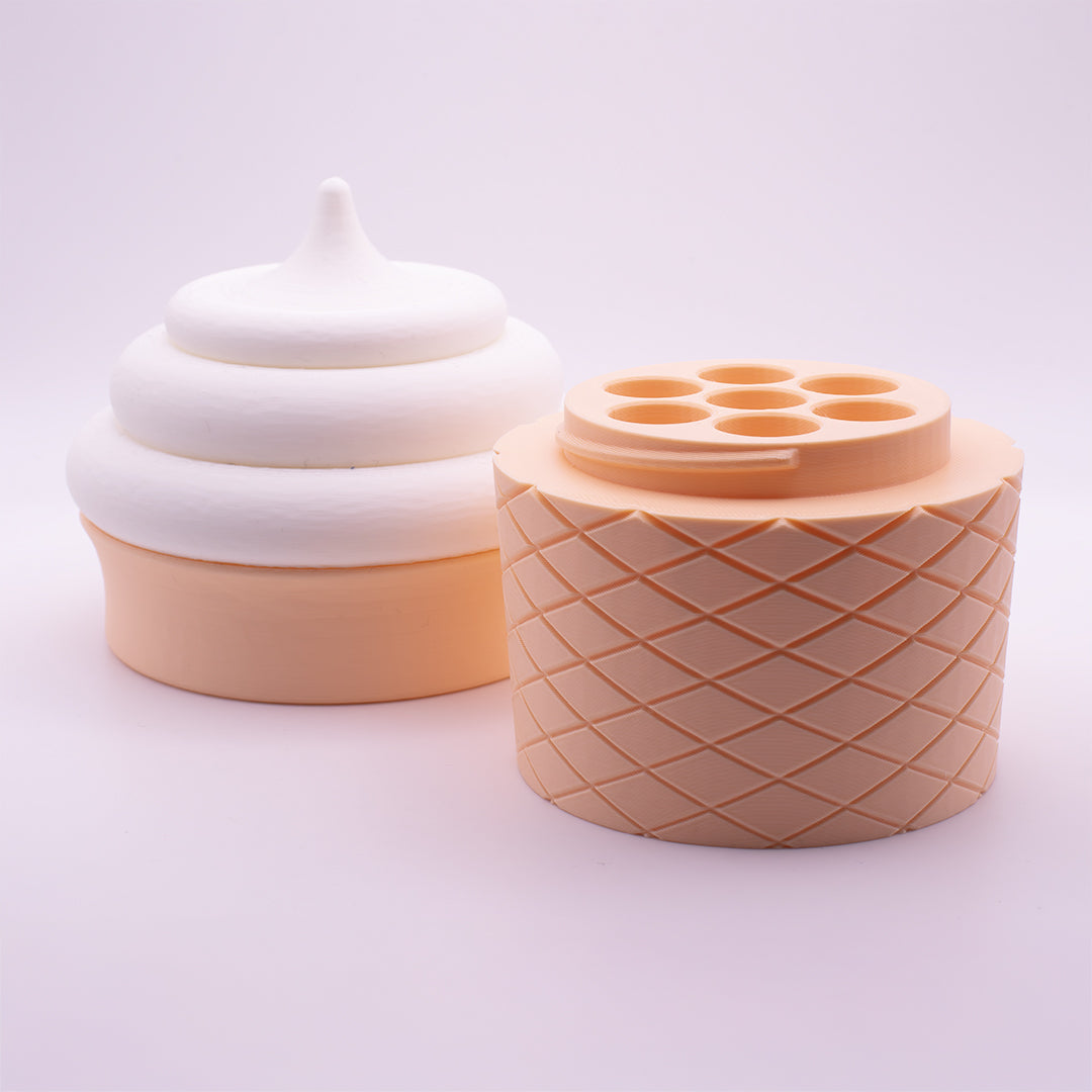 Two sculptural objects from the brand CONEZ on a white background. The left is an ICE CREAM CONE CASE v1 in white with a swirl and pointed top, while the right one is beige with a geometric lattice design and circular top holes. Both feature a glossy finish.