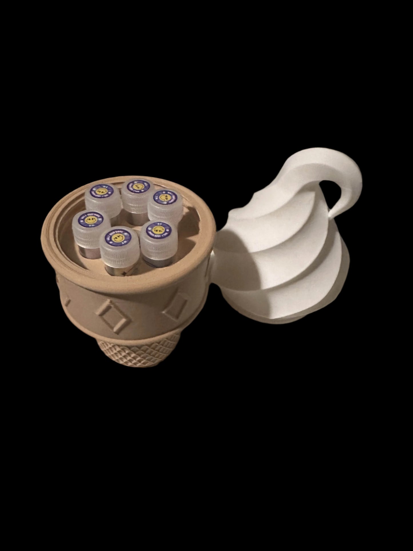 The CONEZ CONE CASE V2 is a brown ice cream cone-shaped container with a swirled top lid. It houses six small jars with colorful lids against a black background, accentuating its whimsical design.