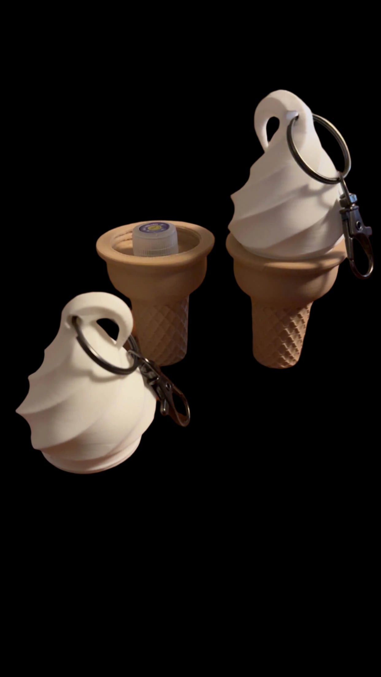 Three CONEZ Mini Cone Keychain Cases on a black background: two resemble vanilla soft-serve cones, and the third is an inverted cone showing a cream-colored interior with a small circular item inside.