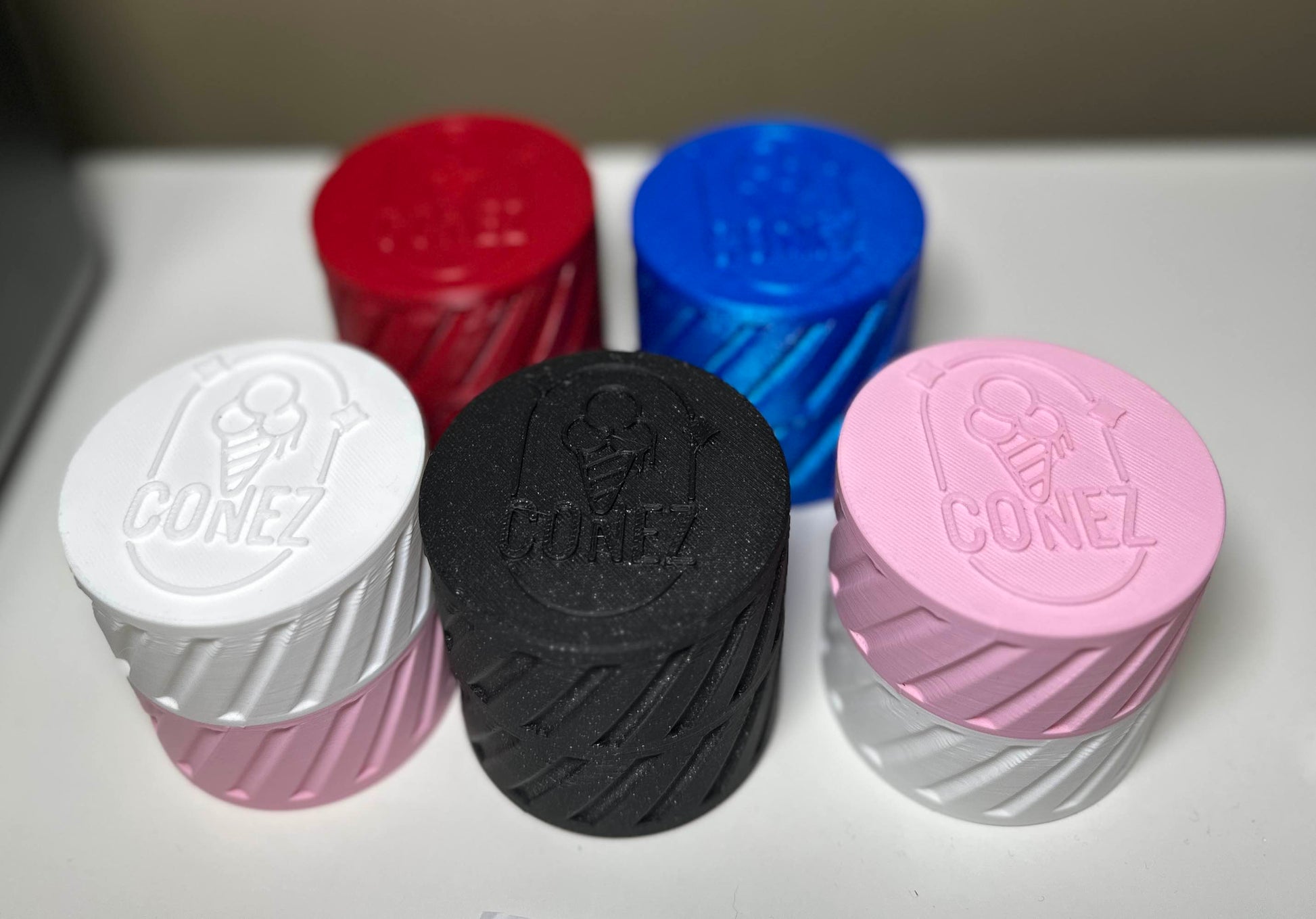 Five textured cylindrical Travel Case V2 Mix & Match containers by CONEZ are featured. They come in white, black, pink, red, and blue with ice cream cone designs and the CONEZ branding on top, all arranged on a white surface.